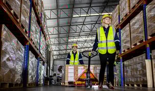 warehouse workers walking through warehouse with pallet